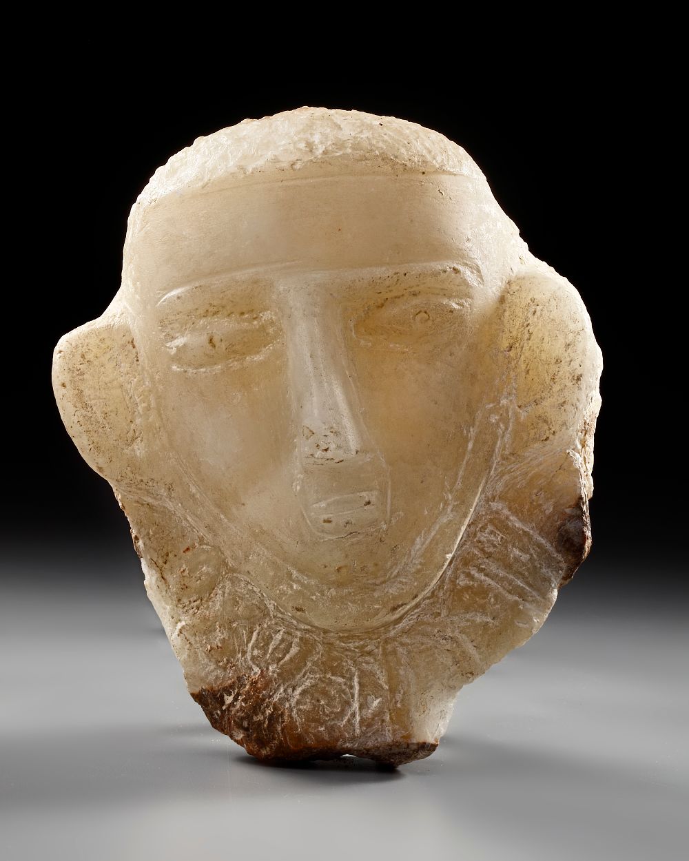 A CARVED ALABASTER FUNERARY PORTRAIT WITH INSCRIPTION TO THE NECK, LATE 1ST MILLENNIUM BC. PROVEN 