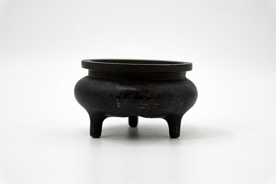 A Chinese tripod patinated bronze incence burner. Front contains calligraphy on the rim. 