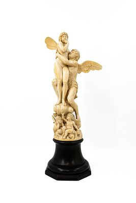 A large and antique French carved ivory group depicting Eros and Psych&eacute; on a cloud with three 