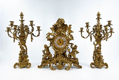 A large and antique French Rococo style gilt bronze mythological figural decorated mantel clock set