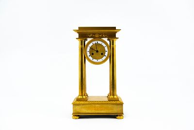 An antique gilt bronze Empire style column mantel clock. 19th century. Condition: pendulum is 