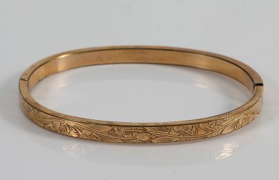 14K GOLD BANGLE BRACELET. Engraved detail along front of bangle; hinged bangle; interior marked 