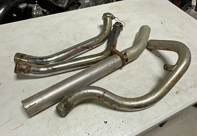 An Assortment of Four Used Motorcycle Exhaust Header Pipes and Heat Shields. A collection of 