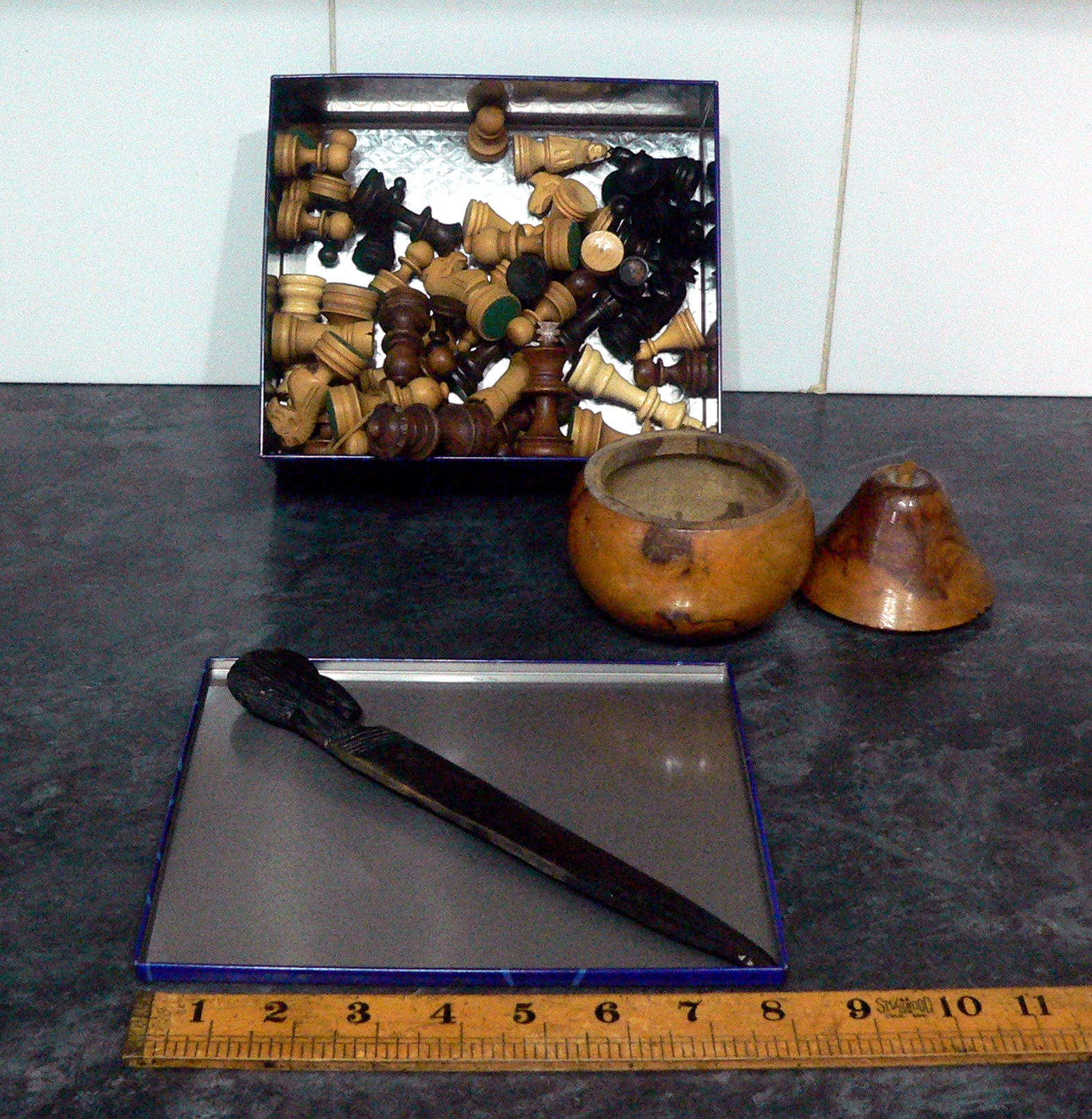 Metal tin containing wooden chess sets (unchecked) a two part wooden pear and a carved ebony wooden knife.