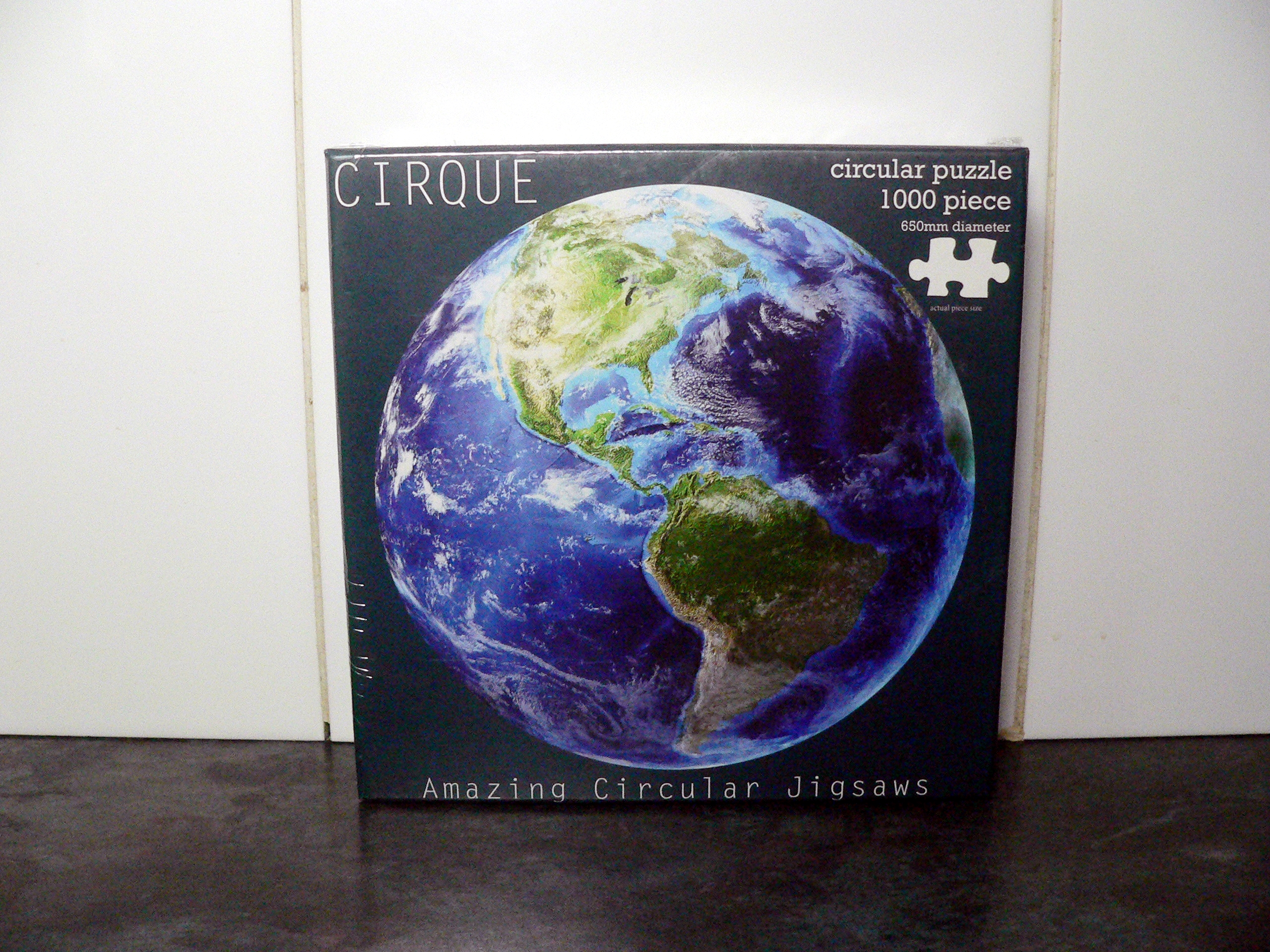 Factory sealed 1000 piece circular jigsaw puzzle.