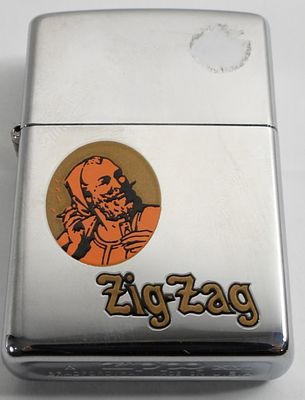 2000 SEALED ADVERTISING ZIG-ZAG ZIPPO. IN A ZIPPO BOX, WITH LOGO ON THE FRONT