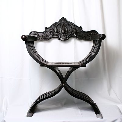 Cadeira de Savonarola antiga em madeira maci&ccedil;a, com espaldar e assento com decora&ccedil;&atilde;o relevada. 