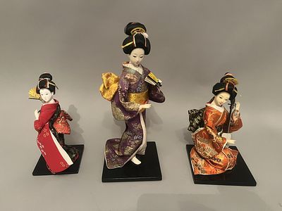 A group of three traditional Japanese decorative dolls, each depicting a female figure in an 