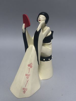 A cream, black, and red Artforum 'Make A Wish' figurine of a woman holding a fan, adorned with 
