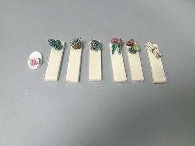 Seven off-white ceramic decorative rests: six rectangular pieces topped with colorful ceramic 