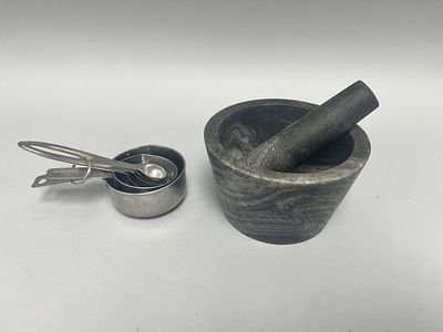 A marble mortar and pestle set, comprising a dark grey and white mottled stone mortar and 