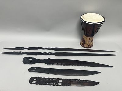 A collection of African carved wooden decorative objects and a djembe-style drum. The 