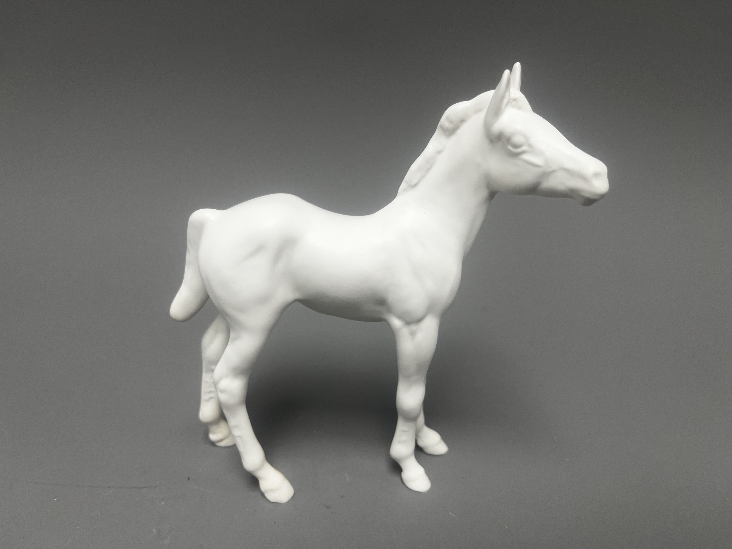 A Beswick ceramic figurine of a standing foal, finished in a matt white glaze