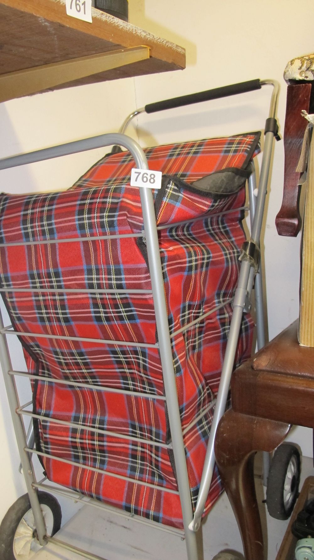 Lot 768: A Folding Two-Wheeled Shopping Trolley with Red Tartan Bag