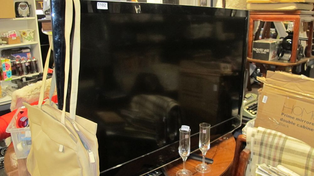 Lot 1102: Large Format Flat Screen Television with Integrated Stand
