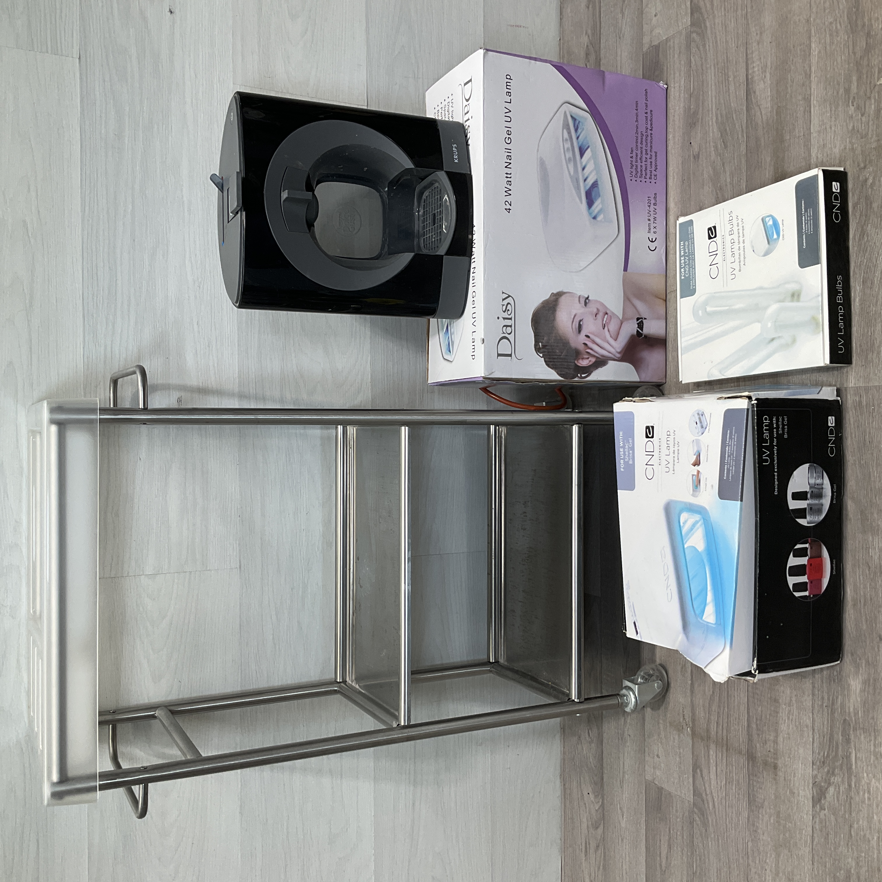 An Assortment of Salon and Household Equipment Including UV Nail Lamps, Coffee Machine, and Stainless Steel Utility Trolley