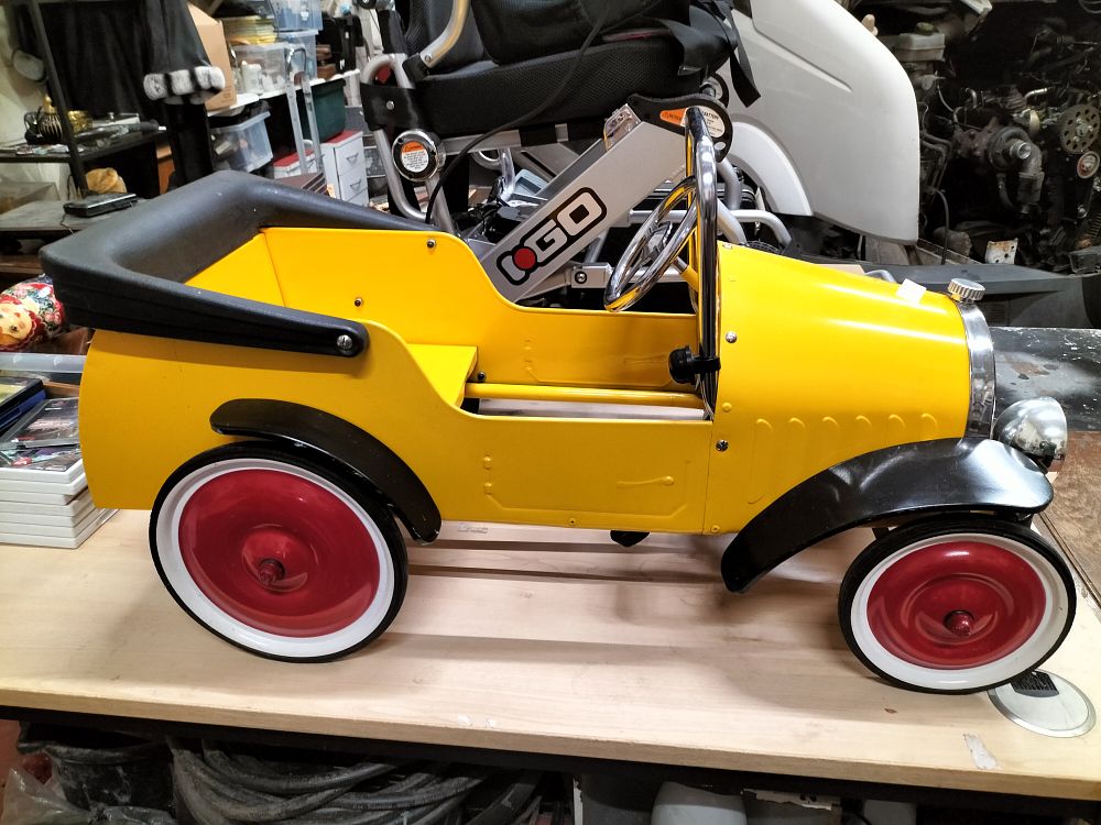 Lot 191 – A vintage style yellow metal pedal car in the style of an Edwardian tourer