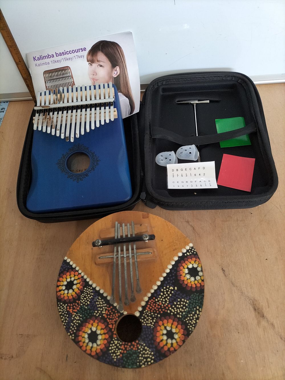Lot 169 – Two Kalimbas Comprising a Modern 17-Key Blue Instrument and a Hand-Painted Circular Example