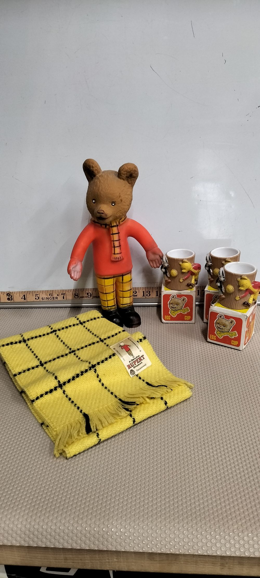 Lot 175 – A Collection of Vintage Rupert Bear Character Memorabilia Including a Vinyl Figure, Egg Cups, and a Wool Scarf