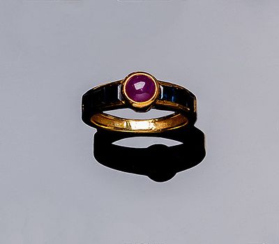 Anillo en oro amarillo 18 K con rubí fino en cabujón circular, sobre banda de zafiros finos 