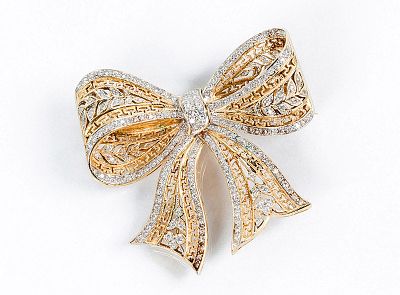 Broche-alfiler en oro amarillo y blanco 18 K, dise&ntilde;o de lazada con grecas caladas y motivos 