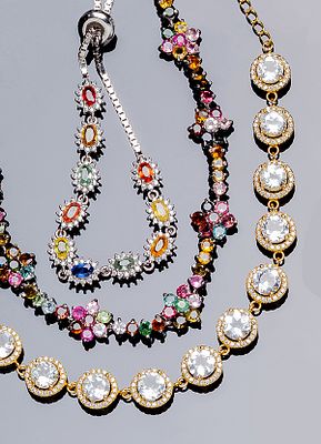 Lote de tres pulseras en plata de ley: una dorada con rosetones de topacios azules y orla de 