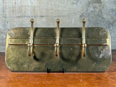 BRASS WALL MOUNT COAT HANGER. This lot features a vintage brass wall mount coat hanger with 