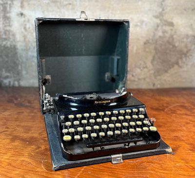 REMINGTON PORTABLE TYPEWRITER. This lot features an antique Remington portable typewriter with a 