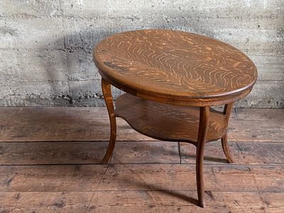 TWO-TIER TIGER OAK SIDE TABLE. This lot features an early 1900s oval two-tier tiger oak side 