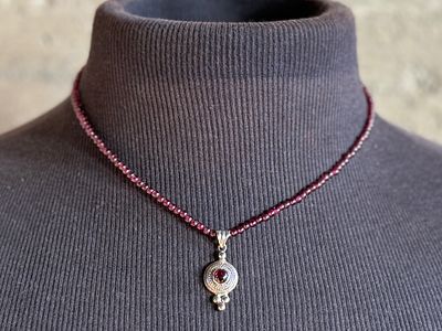 GARNET BEADED NECKLACE . This lot features a vintage garnet beaded necklace with a sterling 