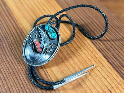 SILVER BOLO TIE WITH TURQUOISE AND CORAL ACCENTS. Silver bolo tie featuring a decorative oval 
