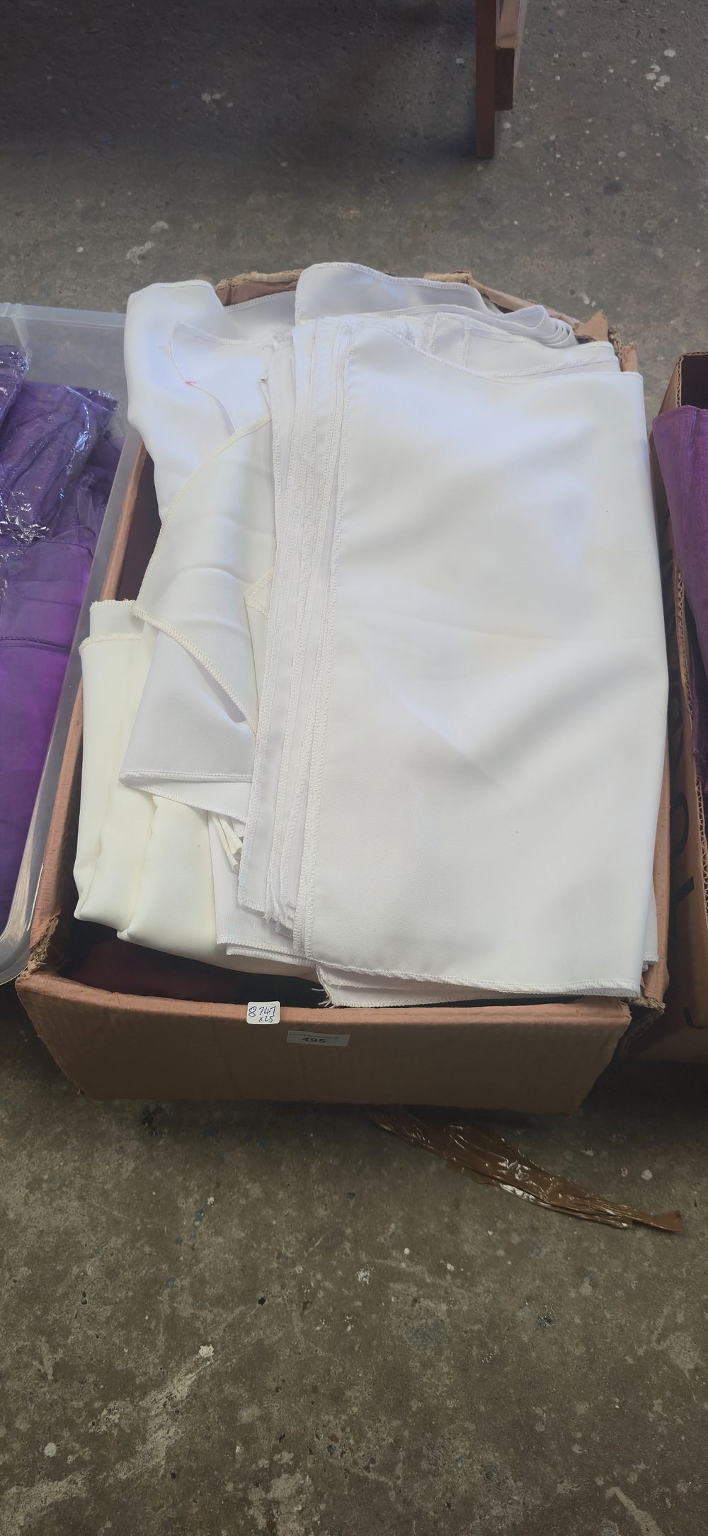 Lot 495: Box containing various coloured tablecloths, white cream, red...