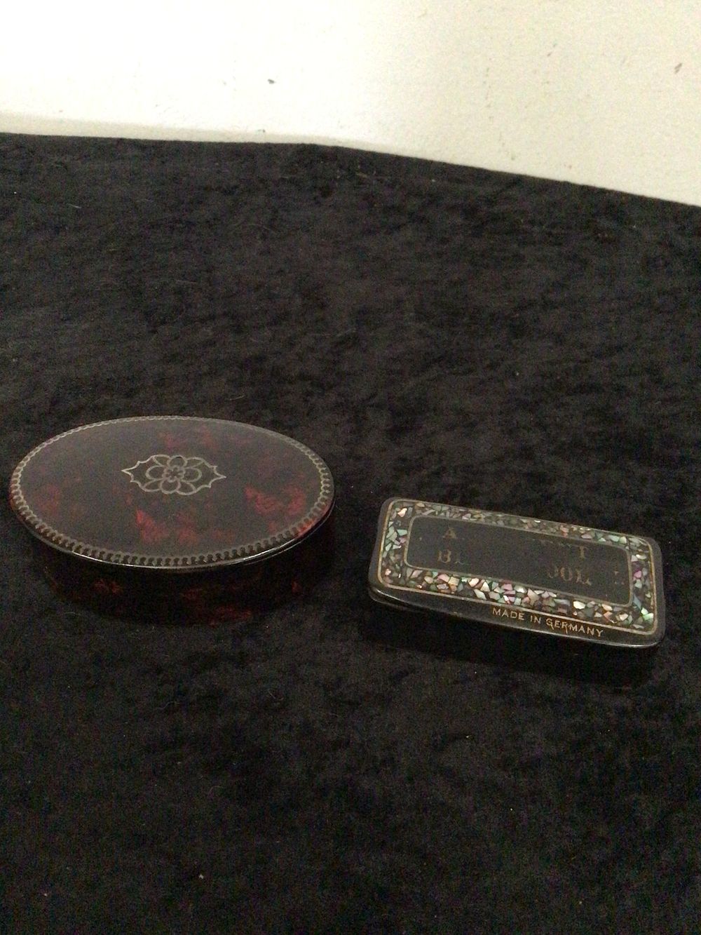 Lot 192: A Pair of Vintage Lidded Boxes, comprising an oval lacquered papier-mâché box with silver inlay and a rectangular metal box with mother-of-pearl inlay