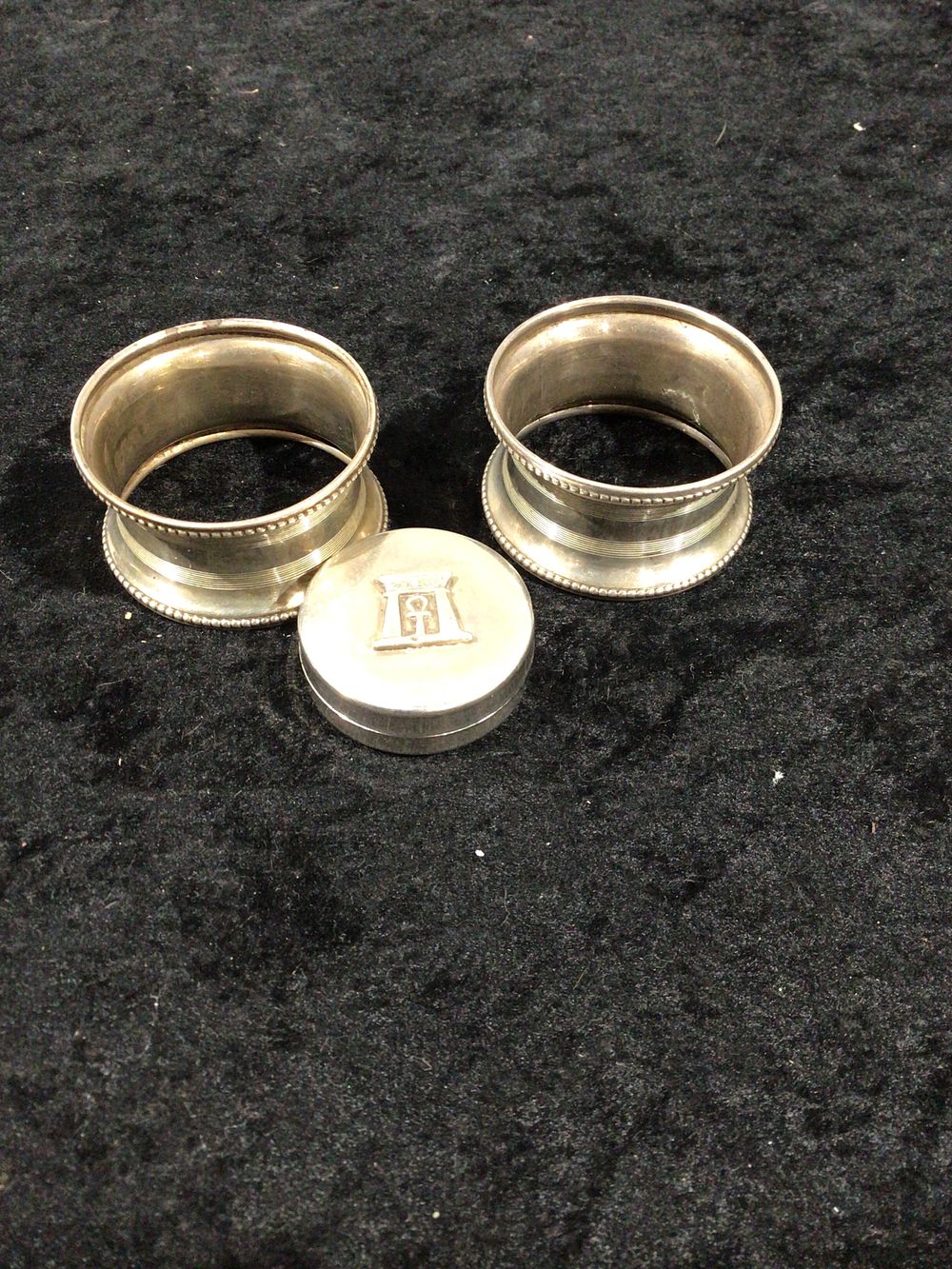 Lot 286: A Set of Three Silver-Toned Metal Napkin Rings and Egyptian Revival Pill Box