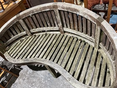 A Weathered Teak Serpentine Garden Bench. A single, serpentine or banana-shaped garden bench 