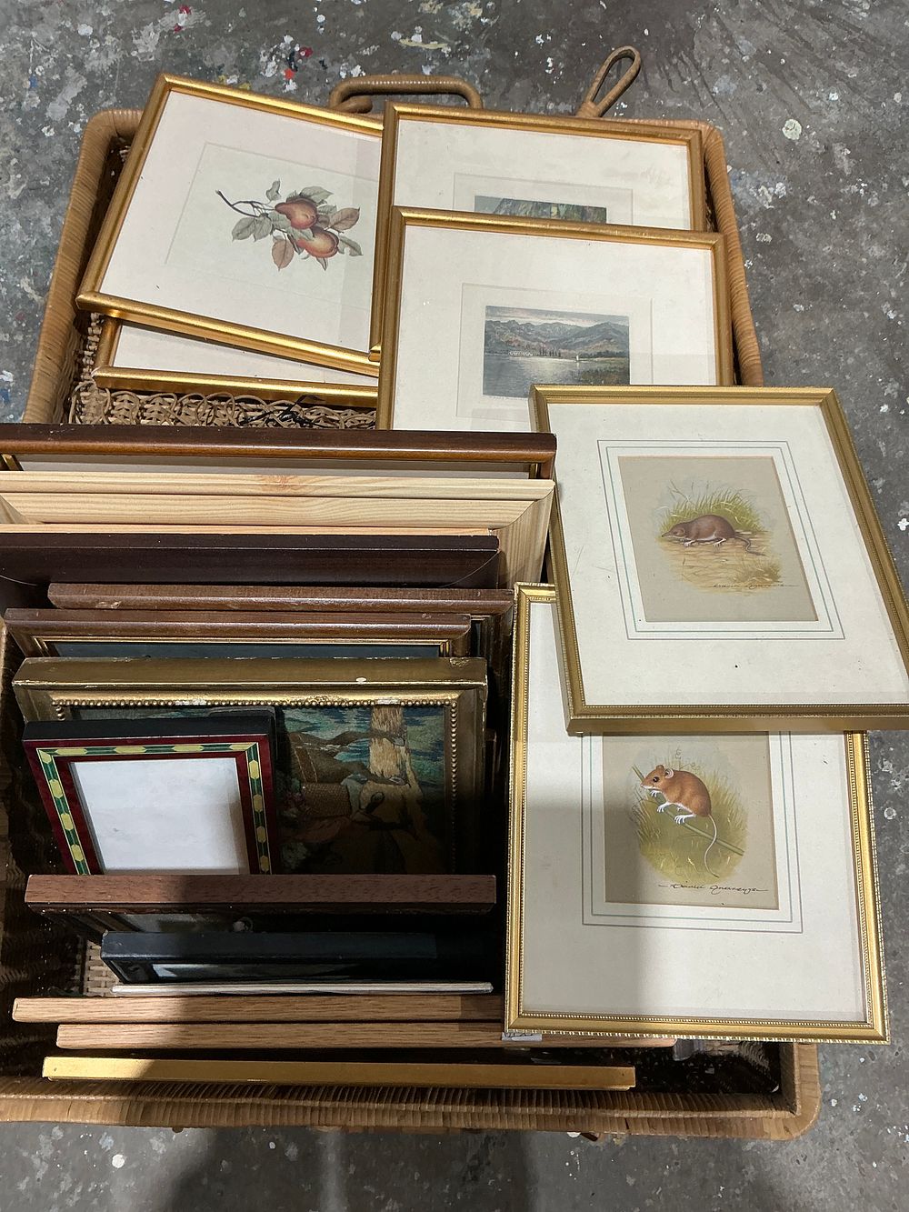 Lot 319: A Collection of 20 Framed Artworks, Loose Frames, and Moulding Pieces in a Wicker Basket