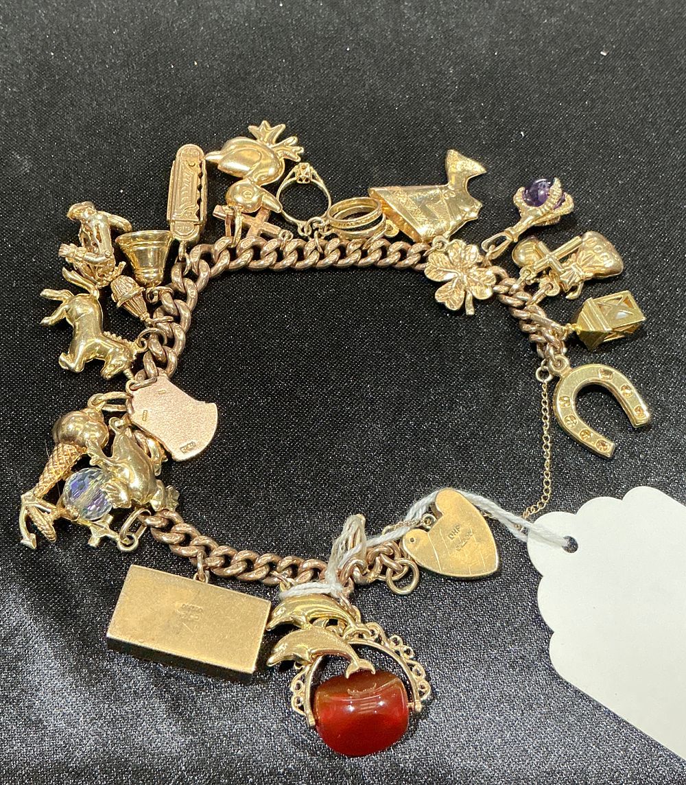 Lot 160: A 9ct yellow gold curb link charm bracelet with an assortment of charms weighing 49 grams