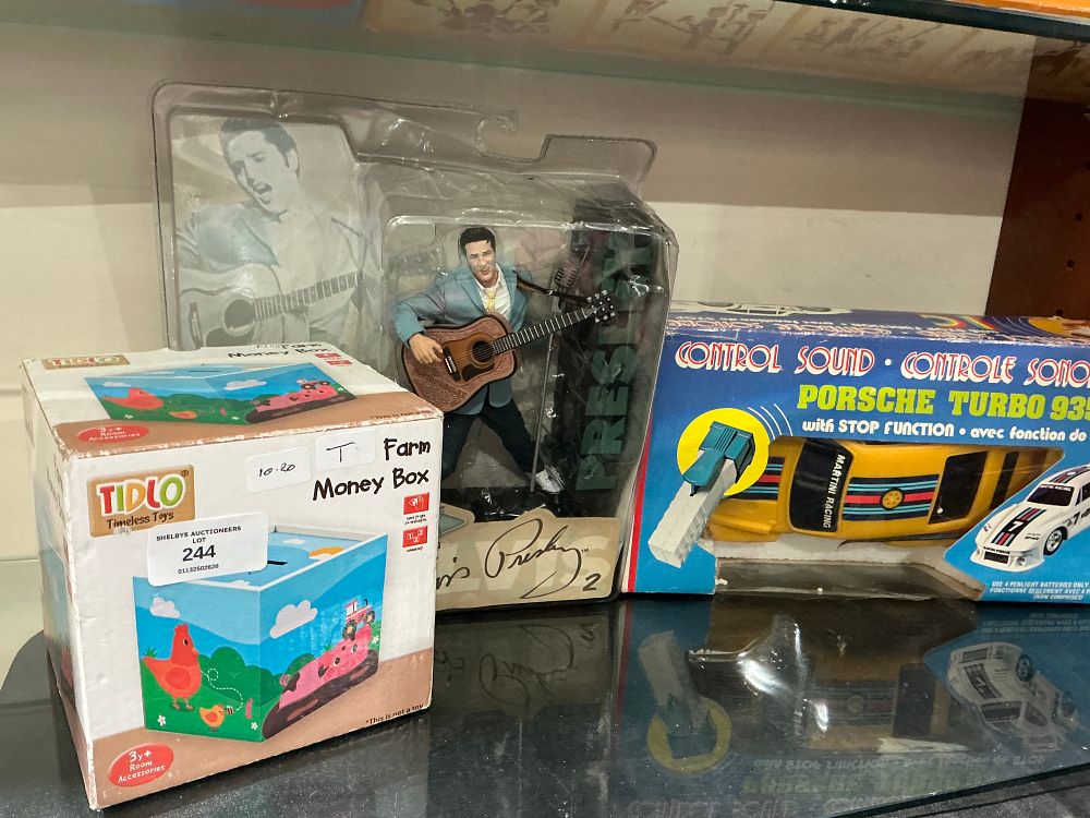 Lot 244: A Trio of Boxed Toys comprising a Tidlo Money Box, an Elvis Presley Action Figure, and a Porsche Turbo 935 Toy Car