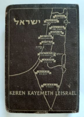 קופת קרן קיימת לישראל (קק"ל) בדימוי ספר עשויה נחושת בכיסוי בד דמוי עור בצבע חום. הקופה כנראה 
