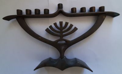 חנוכיה מסיבית מנחושת ישראלית ואיכותית עם מוטיב המנורה. סביבות שנת 1950 . אורך 26 ס"מ, 