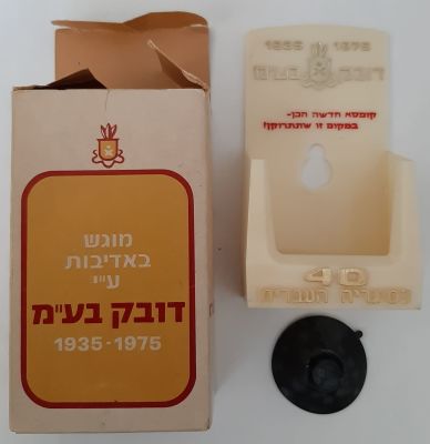 קופסה של דובק חברת סגריות ישראל בתוכה מתקן פלסטיק להנחת קופסת סיגריות. המתקן לצורך לתליה בברכב 