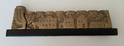 חנוכיה ברונזה נמוכה אך כבדה ומאסיבית. רוחב הבסיס 19 ס"מ. גובה 5 ס"מ כולל הבסיס. חנוכיה לא מצויה.
