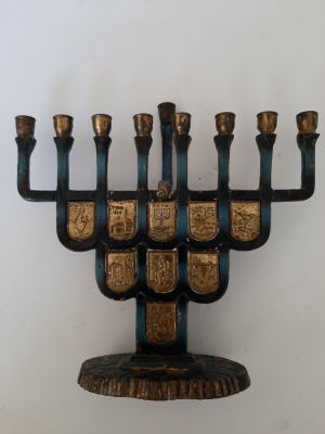 חנוכיה ישראלית עם פלקים של מקומות וסצנות היסטוריות. גובה כ 18 ס"מ, רוחב מוטת הבזיכים כ 16 ס"מ.