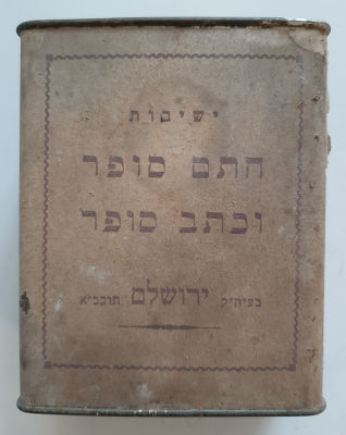 קופה צדקה ישנה עשויה פח ומעטפת נייר. ישיבות חתם סופר וכתב סופר