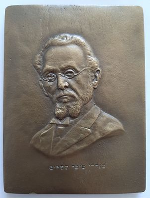 שמואל קרצ'מר - אמן בצלאל. תבליט פלק ברונזה עם דמותו של הסופר מנדלי מוכר ספרים. חתום באיזור 