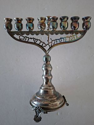 חנוכיה כסף זקופה. משקל 116 גרם. גובה 16.5 ס"מ, רוחב כ 15.5 ס"מ עם הכיתוב הנרות הללו קודש הם.