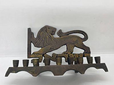 חנוכיה פליז תוצרת ישראל / לא חתומה 
עם אריה העומד על כיתוב ישראל ואוחז באות ל . פטינה ישנה 