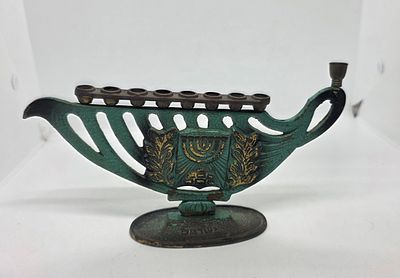 חנוכיה מיוחדת בצורה של כד שמן . עם עיטור של מנורת הקנים ולצידה ענפי עץ זית . 
חנוכייה לא 