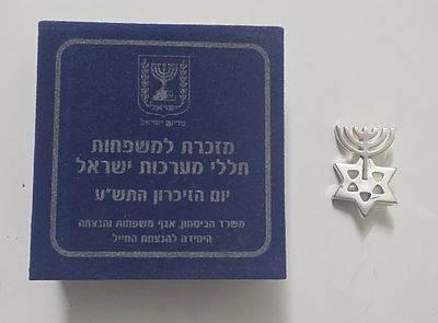סיכן זיכרון מתכת לבנה . בעיצוב נהדר של מנורה מוצמדת למגן דוד. נתון באריזה המקורית. מזכרת למשפחות 