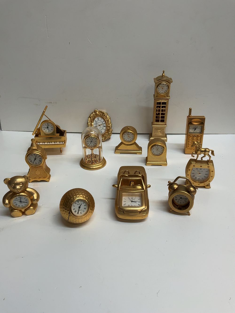Lot 242: A Collection of Thirteen Miniature Gold-Tone Novelty Quartz Desk Clocks including Bulova and Widdop Examples